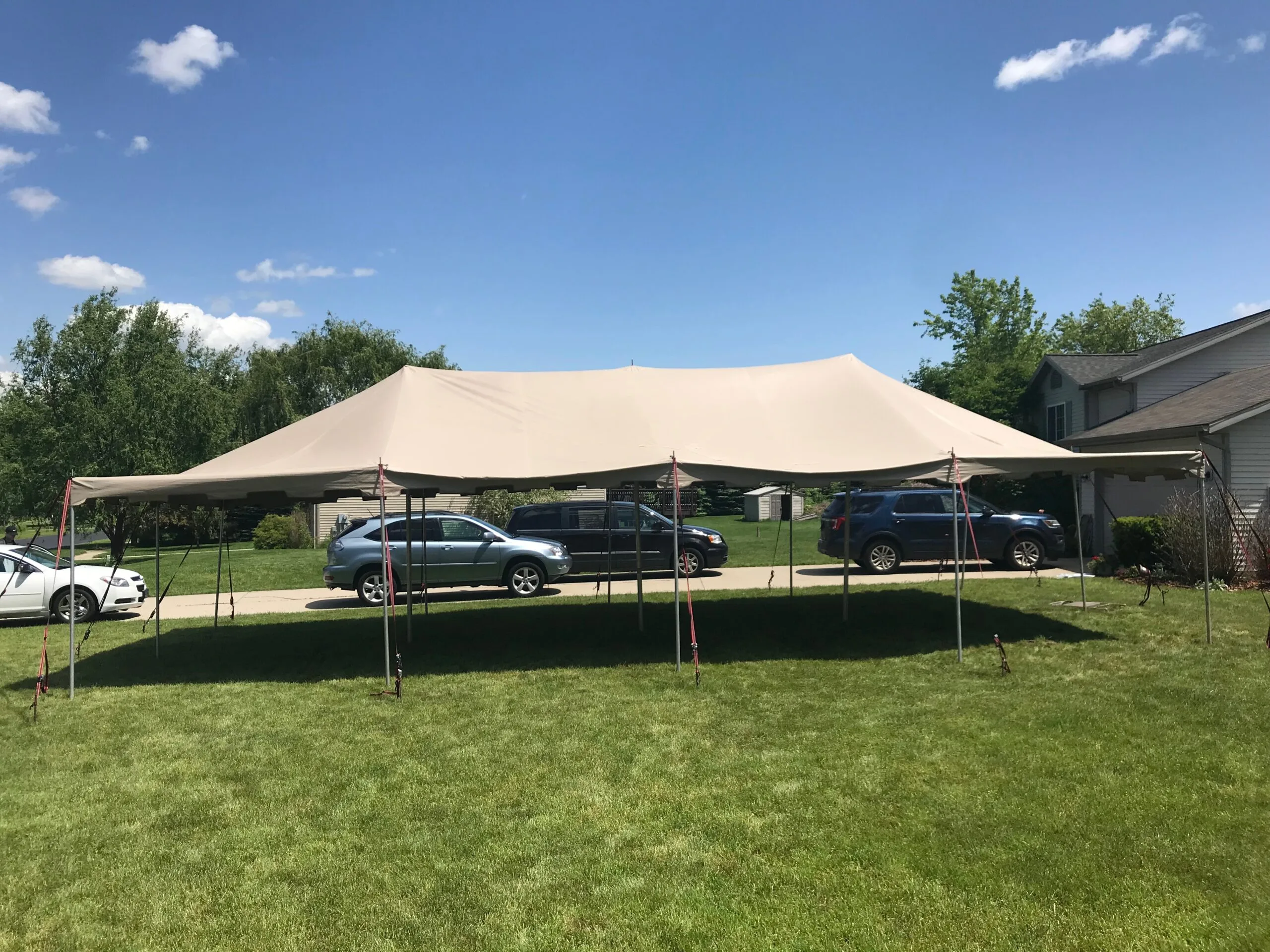 Beige pole tent set up in a residential yard